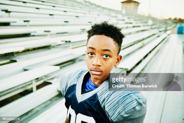 portrait of young football player standing on stadium bleachers before football game - american football uniform stock pictures, royalty-free photos & images