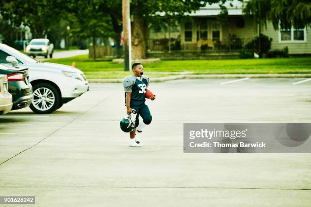 young football player walking across parking lot before football game - footballtrikot stock-fotos und bilder