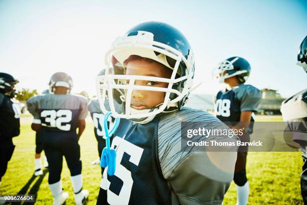 portrait of young football player standing on field with teammates before game - american football game stockfoto's en -beelden