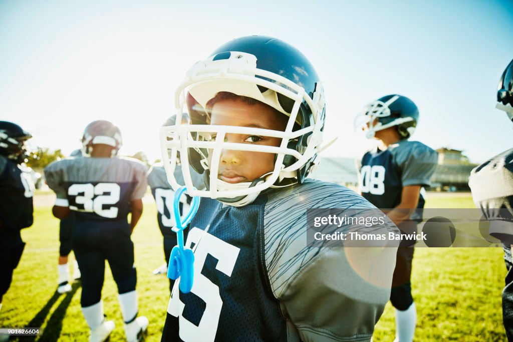 Portrait of young football player standing on field with teammates before game