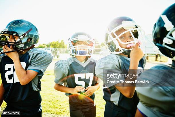 Young football players standing on field during practice listening to instructions from coach