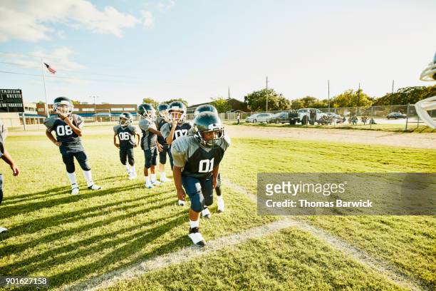young football player preparing to run passing drill during football practice with teammates - boy in hard hat stock-fotos und bilder