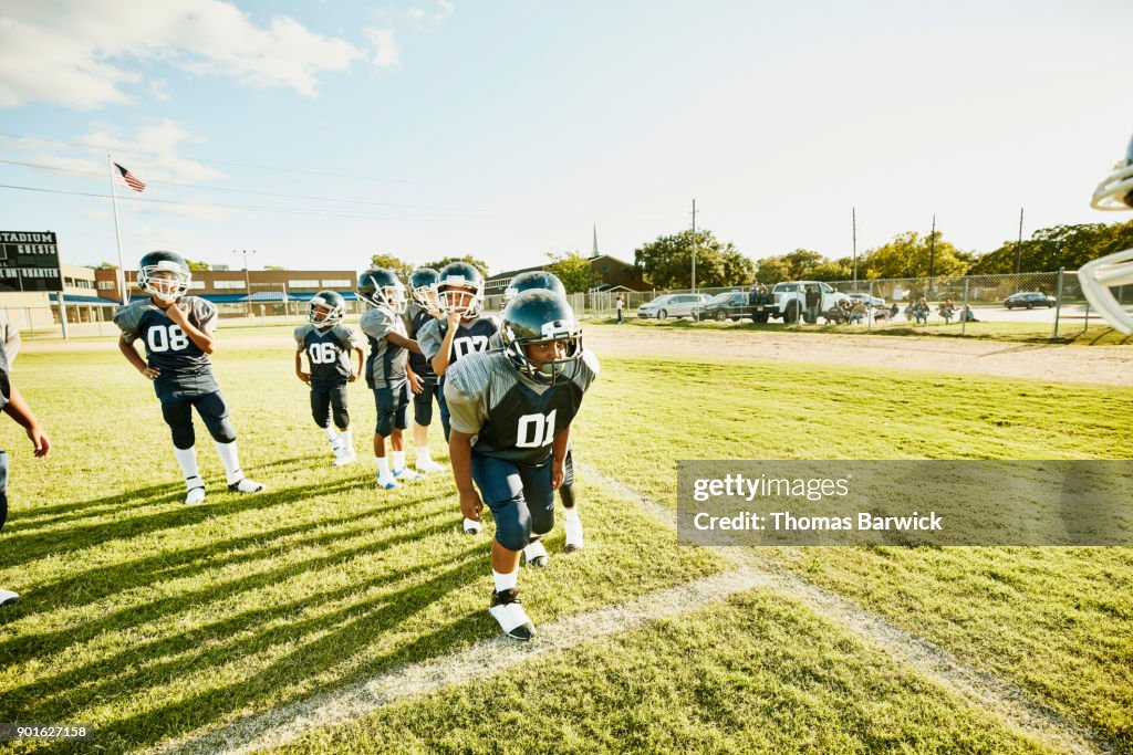 Young football player preparing to run passing drill during football practice with teammates