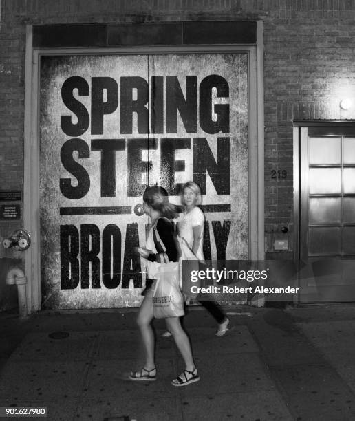 Visitors to New York City walk past the entrance to the Walter Kerr Theatre where singer Bruce Springsteen is performing in residency through June...