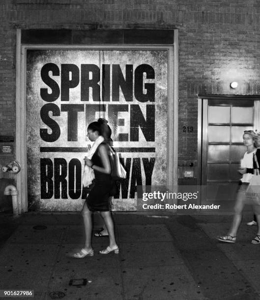 Visitors to New York City walk past the entrance to the Walter Kerr Theatre where singer Bruce Springsteen is performing in residency through June...