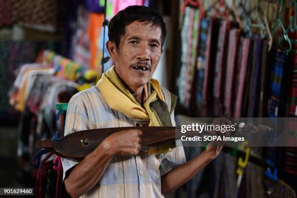 Man playing traditional Batak musical instrument in a local market in Samosir. The Lake Toba in the north of Sumatra as been formed during the...