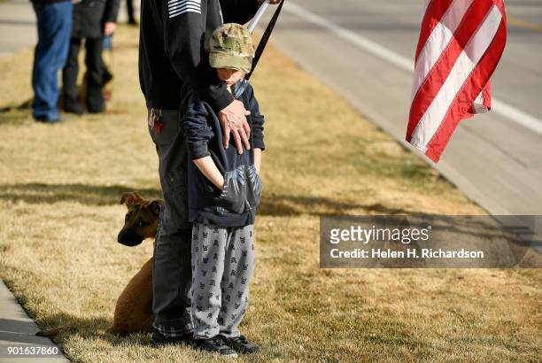 Craig Silber with his son James, 7 and dog Boston, holds an American flag as he pays respects outside of Cherry Hills Community Church during the...