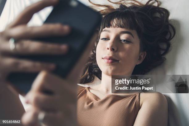 teenage girl on smartphone - girl in her bed stockfoto's en -beelden