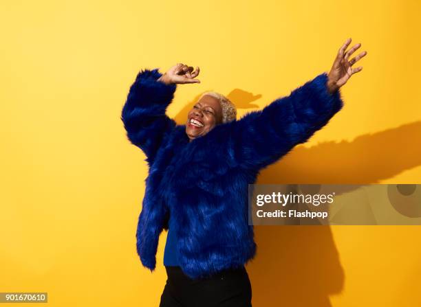 portrait of a mature woman dancing and laughing - woman in fur coat stock-fotos und bilder
