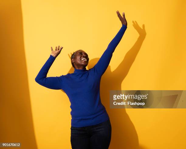 portrait of a mature woman dancing and laughing - arms raised stock pictures, royalty-free photos & images