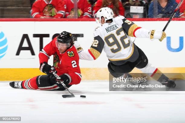 Duncan Keith of the Chicago Blackhawks and Tomas Nosek of the Vegas Golden Knights lose control while chasing the puck in the first period at the...