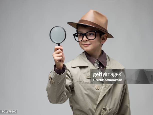 poco niño mirando a través de lupa - detective fotografías e imágenes de stock