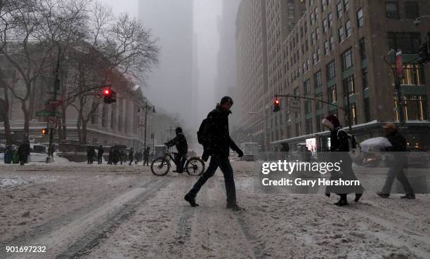 People cross a snow covered 42nd Street during a winter storm called a "bomb cyclone" on January 4, 2018 in New York City.