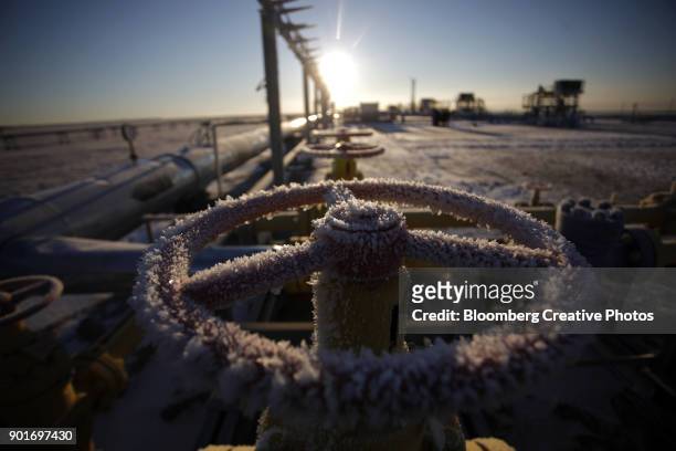 ice sits on a valve control wheel connected to pipe work - russia foto e immagini stock