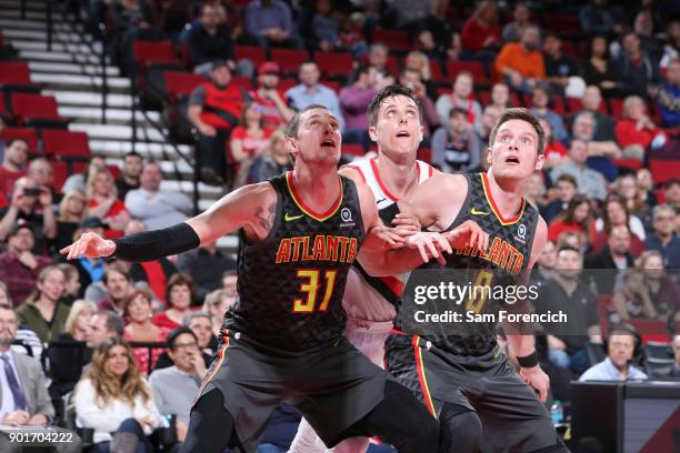 Mike Muscala and Luke Babbitt of the Atlanta Hawks box out Zach Collins of the Portland Trail Blazers on January 5, 2018 at the Moda Center in...