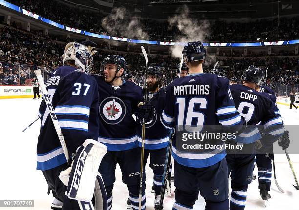 Marko Dano of the Winnipeg Jets congratulates goaltender Connor Hellebuyck as they celebrate a 4-3 victory over the Buffalo Sabres at the Bell MTS...
