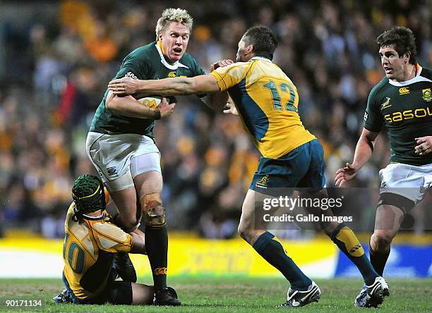 Jean de Villiers of the Springboks is tackled by Matt Giteau and Adam Ashley-Cooper of the Wallabies during the 2009 Tri-Nations series match between...