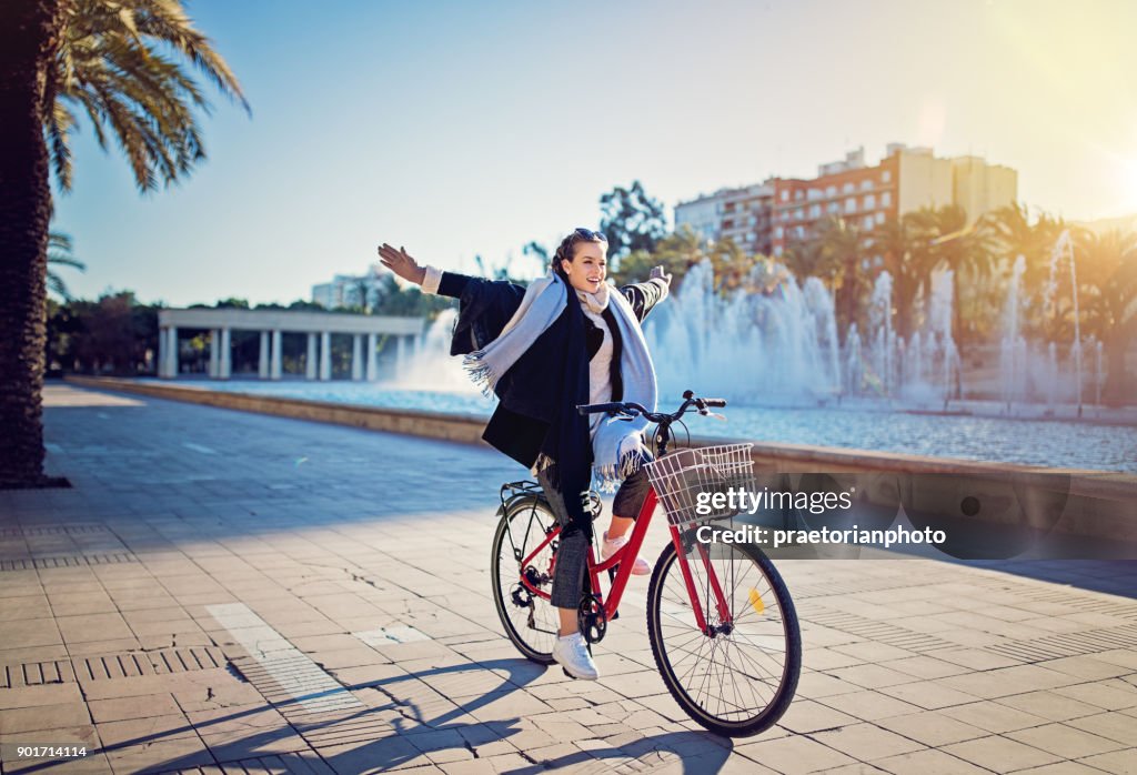 Young girl is riding a bicycle without hands in the park