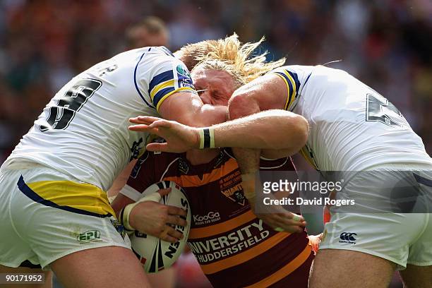 Eorl Crabtree of Huddersfield is halted by Michael Cooper and Paul Johnson of Warrington defence during the Carnegie Challenge Cup Final between...