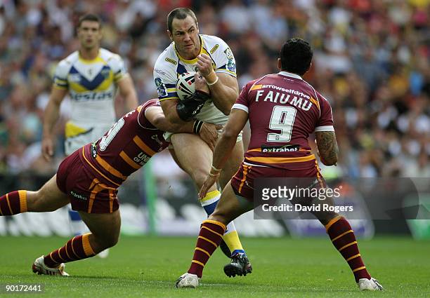 Adrian Morley of Warrington is brought down by Scott Moore L) and David Faiumu of Huddersfield during the Carnegie Challenge Cup Final between...