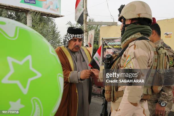 An Iraqi man gives a soldier a national flag at a checkpoint in the capital Baghdad on January 6 during festivities marking Iraq's Army Day. / AFP...
