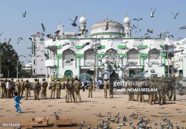Indian police personnel stand guard in front of a mosque as members of Muslim organisations prepare to protest against the proposed 'Triple Talaq...