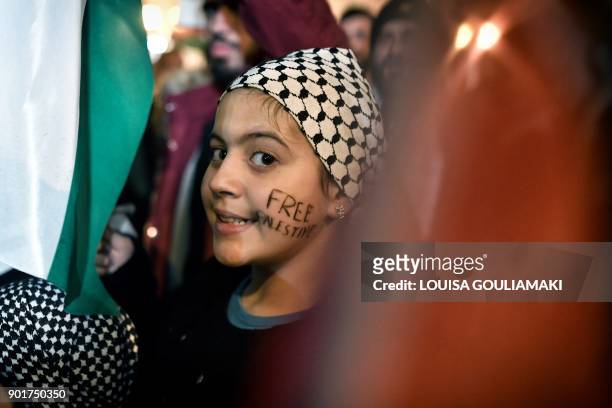Girls stands with the letters 'Free Palestine' on her cheek as Palestinians living in Greece protest near the US embassy in Athens on December 15,...