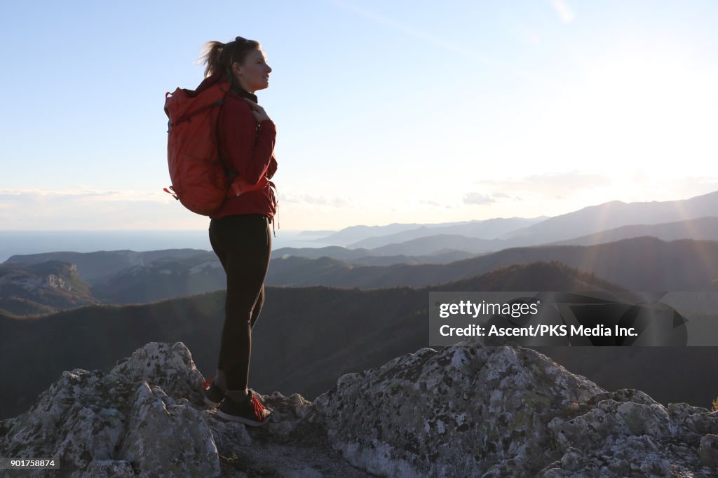 Female hiker traverses rock ridge, nears summit