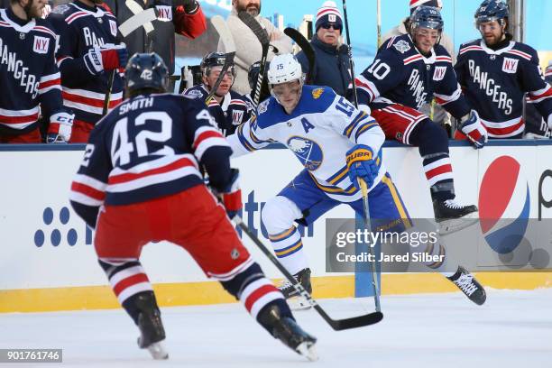 Jack Eichel of the Buffalo Sabres skates with the puck against Brendan Smith of the New York Rangers during the 2018 Bridgestone NHL Winter Classic...