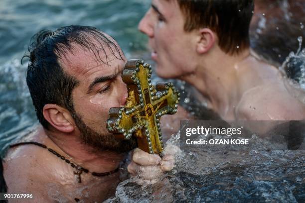 Greek Orthodox swimmers kiss a wooden cross retrieved from the Bosphorus river's Golden Horn, as part of celebrations of the Epiphany day at the...