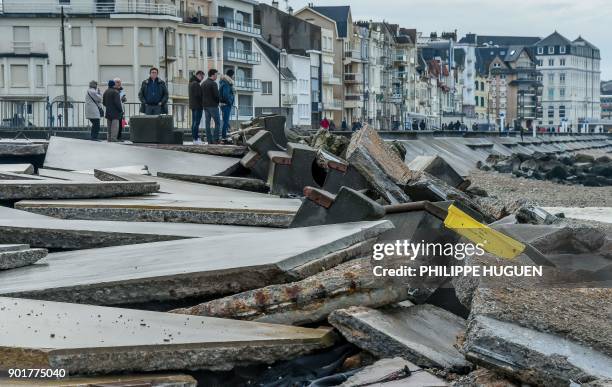 People look at the damaged seawall caused by the Storm Eleanor which swept through Europe, in Wimereux, northern France, on January 6, 2018.