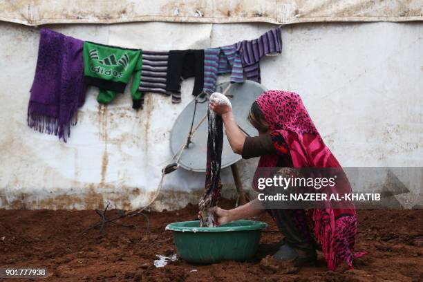 Displaced Syrian woman from Idlib province washes clothes at a makeshift camp near the rebel-held town of Azaz in northern Syria on January 6, 2018.