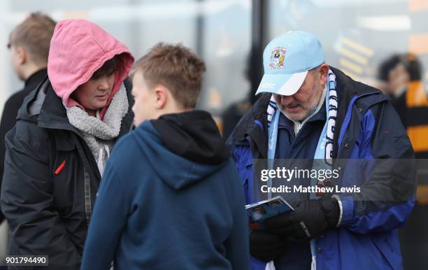 Coventry City fan reads the matchday programme prior to The Emirates FA Cup Third Round match between Coventry City and Stoke City at Ricoh Arena on...