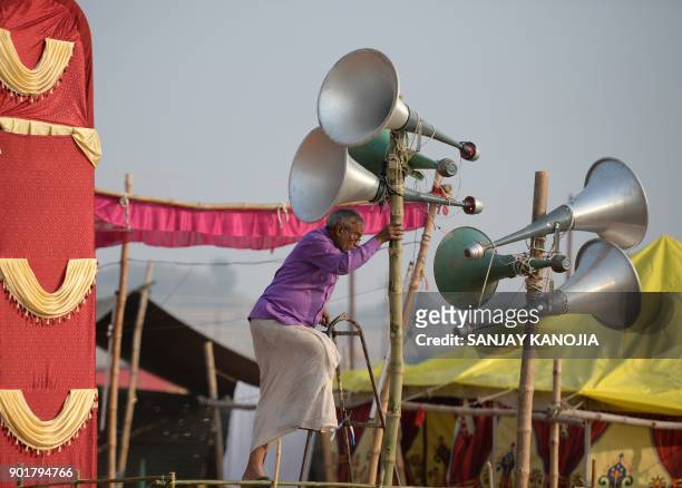 An Indian worker adjusts loudspeakers at a camp during the Magh Mela festival in Allahabad on January 6, 2018. The Magh Mela is held every year on...