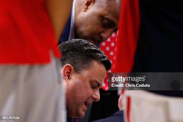 Head coach Sean Miller of the Arizona Wildcats and assistant coach Lorenzo Romar draw a play during a break in the second half of the college...