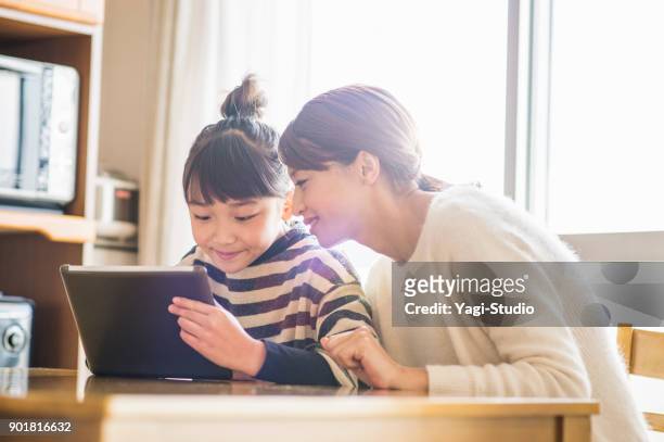 mother and daughter playing with a digital tablet in room - childhood stock pictures, royalty-free photos & images