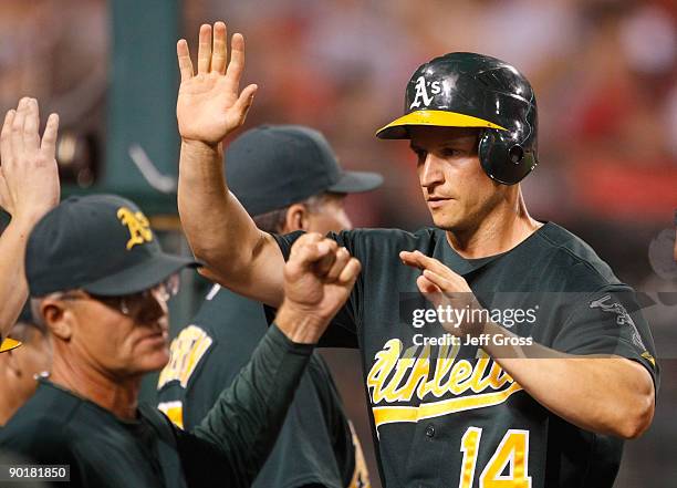 Mark Ellis of the Oakland Athletics receives high fives from his teammates after scoring on a wild pitch in the seventh inning against the Los...