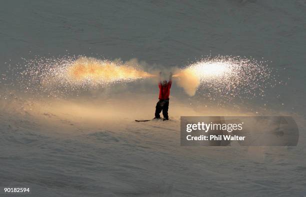 Byron Wells of New Zealand skies down Coronet Peak while holding flares during the Closing Ceremony for the Winter Games NZ at Coronet Peak on August...