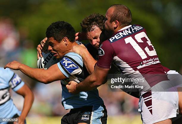 Anthony Tupou of the Sharks is tackled by Josh Perry and Glenn Stewart of the Sea Eagles during the round 25 NRL match between the Manly-Warringah...