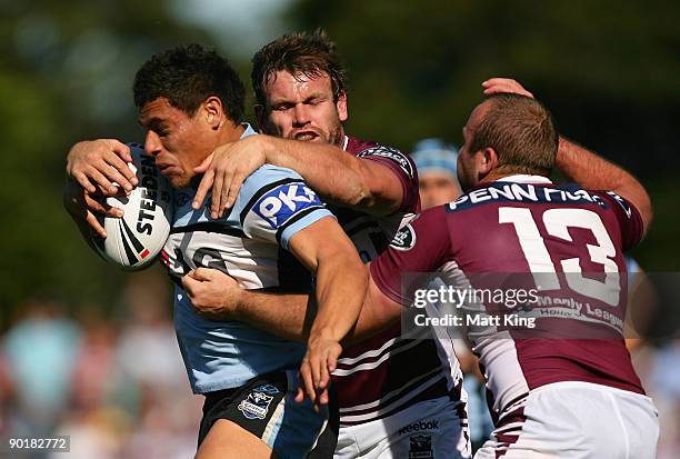 Anthony Tupou of the Sharks is tackled by Josh Perry and Glenn Stewart of the Sea Eagles during the round 25 NRL match between the Manly-Warringah...