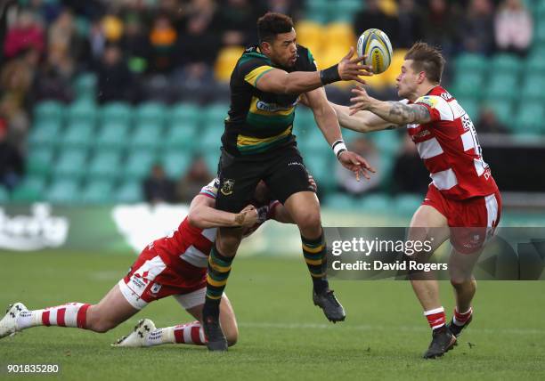 Luther Burrell of Northampton off loads the ball as Jason Woodward tries to intercept during the Aviva Premiership match between Northampton Saints...