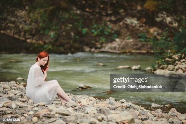 femme assise près de la rivière dans les montagnes - pureté photos et images de collection