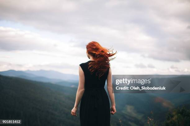 mujer en vestido negro caminando en las montañas y mirando a ver - pelirrojo fotografías e imágenes de stock