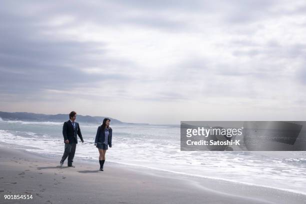 couple étudiant du secondaire marchant sur la plage - jeune fille asiatique bord de mer photos et images de collection