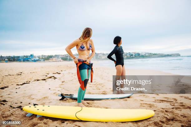two females preparing for morning surfing session - australia training session stock pictures, royalty-free photos & images