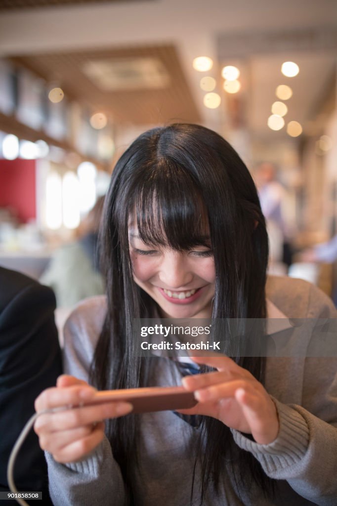 High school student girl taking picture of food in cafe