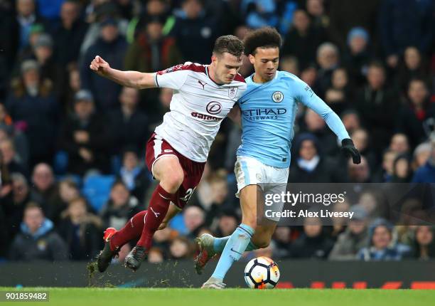 Leroy Sane of Manchester City runs with the ball under pressure from Kevin Long of Burnley during The Emirates FA Cup Third Round match between...