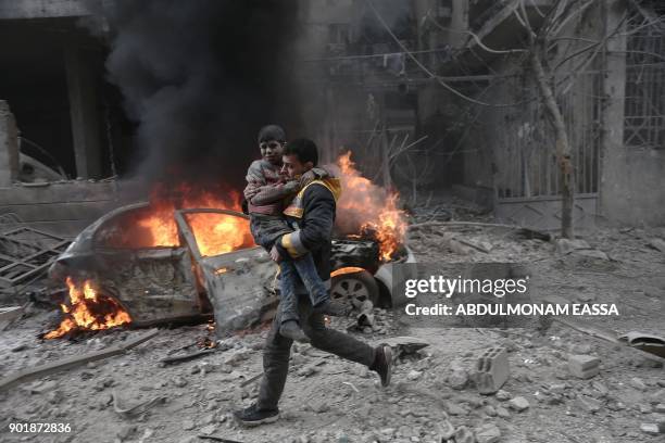 Syrian paramedic carries an injured child following reported bombardment by Syrian and Russian forces in the rebel-held town of Hamouria, in the...