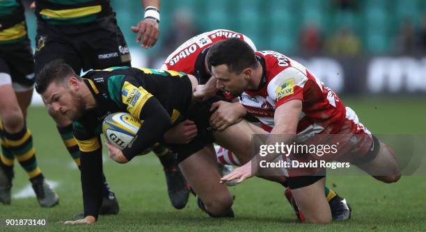 Rob Horne of Northampton is tackled by Tom Marshall and Andy Symons during the Aviva Premiership match between Northampton Saints and Gloucester...