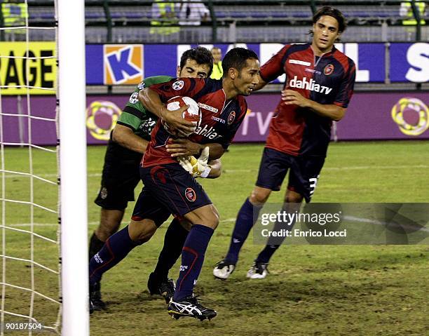 Goalkeeper Gianluca Curci of Cagliari grapples with Neves Capucho Jeda of Cagliari after Jeda had scored from the penalty spot during the Serie A...